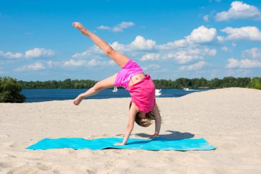 Yazın spor ve aktif oyun kavramı. Kız plajda dinlenirken jimnastik yapıyor..