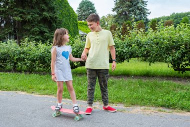 Mutlu çocuklar parkta oynar ve kaykaya biner..