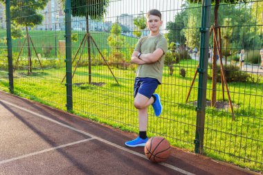 Güneşli bir günde basketbol sahasında genç bir çocuk..