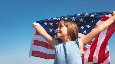 Doğasında Amerikan bayrağı olan mutlu bir çocuğun açık hava portresi. Özgürlüğün sembolü