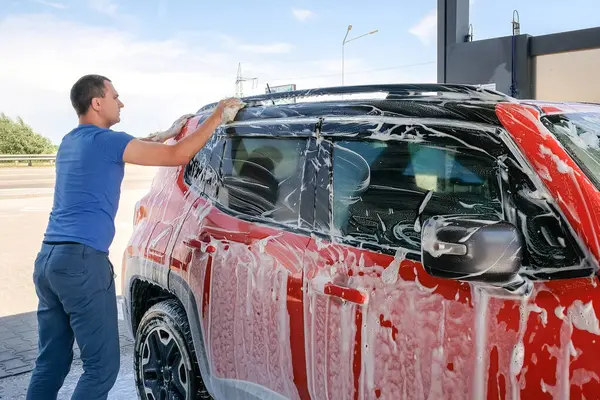 一个人用肥皂洗一辆红色的汽车 泡沫汽车 — 图库照片