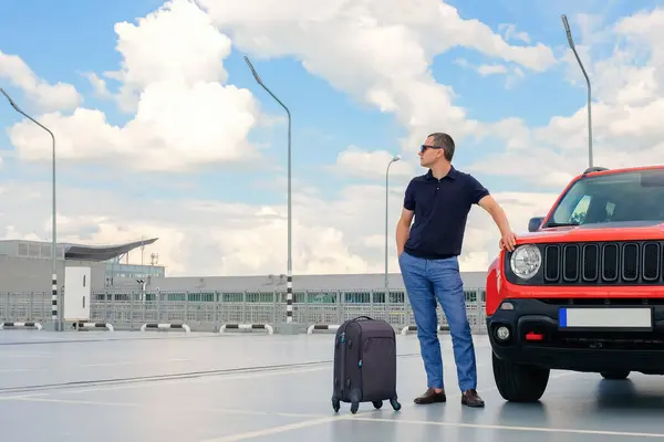 旅行概念 年轻的商人站在他的汽车旁边 在机场停车场拿着行李 公务旅行 — 图库照片