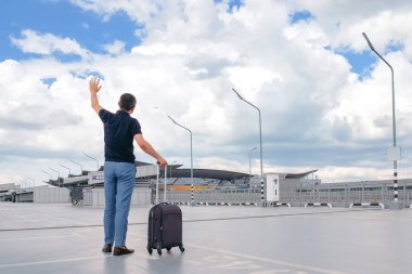 Havaalanı bölgesinde bavullu bir erkek yolcu. Tatil konsepti, iş gezisi