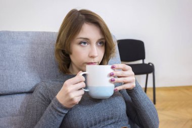 Ofiste elinde bir fincan çayla genç bir kız. Yemek molası..