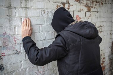 Terk edilmiş bir binada beyaz bir duvara yaslanmış bir bağımlı. Yan görüş. Kes şunu..