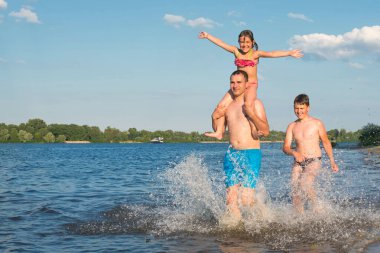 Suda aile kumsalı oyunları. Aile güneşli bir günde sahil boyunca koşar, tatil, tatil, oyunlar