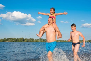 Tatildeki aile su oyunları. Kumsalda mutlu bir aile, tatil, spor, aktif yaşam tarzı..