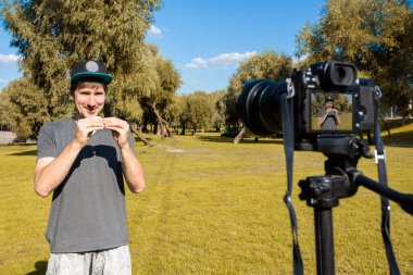 Genç bir adam parkta bir kamerayla bir video kaydediyor. Bağımsız olarak uzak çalışma