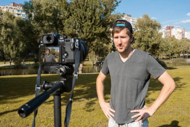 Genç bir adam güneşli bir günde dışarıda kamerayla bir video kaydediyor. Uzak yaşam biçimi.