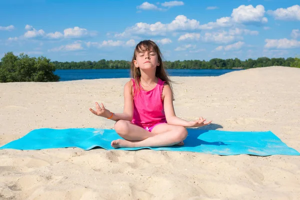 Küçük kız sahilde jimnastik yapıyor. Spor, spor, spor, yoga, aktif yaşam tarzı konsepti