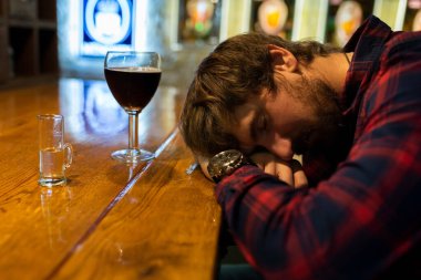 Sarhoş bir genç adam bir barda bir tezgahın üzerinde uyuyor. Alkol, alkol bağımlılığı, yalnızlık, kriz, işsizlik. Sağlıksız yaşam tarzı kavramı