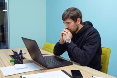 Ofiste çalışan genç bir işadamı dizüstü bilgisayara bakıyor ve e-postaları okuyor. Danışmanlık, eğitim, iş.