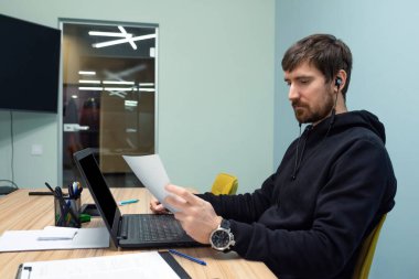 Genç bir adam büroda evraklarla birlikte çalışıyor. İş, iş adamı, iş adamı.