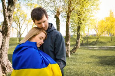 Güneşli bir günde Ukrayna bayrağıyla birlikte parkta genç bir çift.