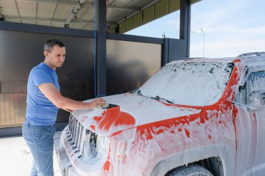 Bir adam araba yıkamada bir süngerle araba yıkar. Dışarıdaki köpüklü araba..