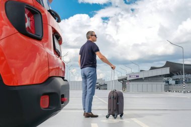 Açık otoparkta bavullu bir adam var. İş gezisi, iş gezisi, tatil konsepti.