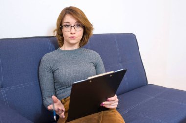 Genç bir kadın psikolog not alır ve kameraya bakar. Profesyonel psikoloğun sağlık hizmeti konsepti.