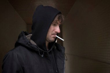 Sokakta kapüşonlu bir adam. Alkolizm ve uyuşturucu bağımlılığı kavramı. Depresyon, işsizlik, sosyal sorunlar.