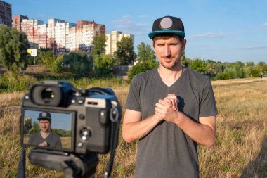 Bir hipster blogcusu güneşli bir günde parkta bir blog için video çekiyor. Video kaydı, serbest çalışma