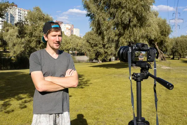 Genç adam blogger kayıt video kamera park önünde. Blogger kavramı.