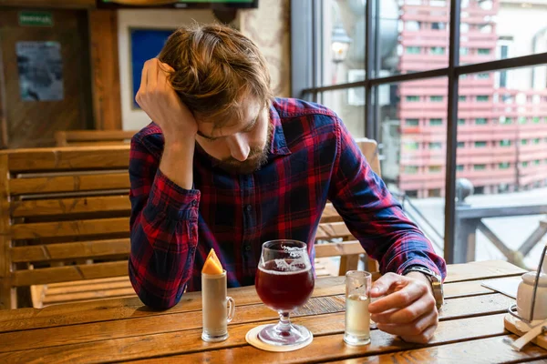 A drunk man at a bar, sitting alone at a table. Fight against alcohol addiction, crisis, unemployment, loneliness, depression