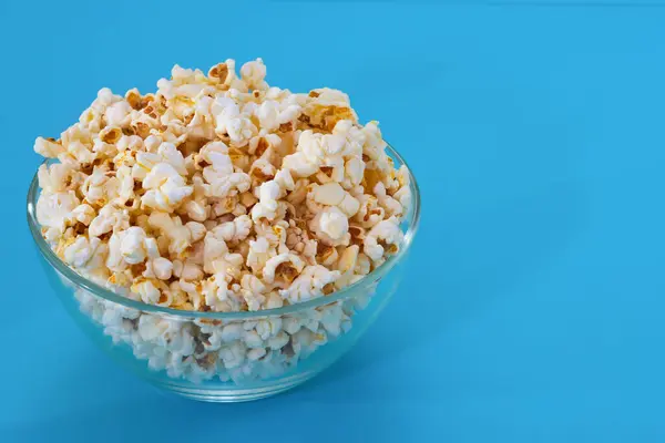 Popcorn in a bowl on a blue background.