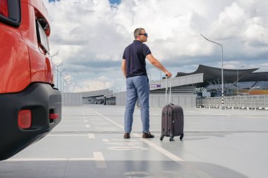 Havaalanı otoparkında bavullu genç bir adam. Arkadan bak. Seyahat kavramı.