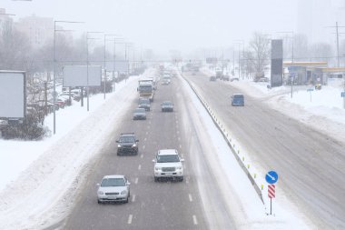 Ukrayna, Kiev. 10 Haziran 2019, kışın şehir trafiği. Karlı bir yolda giden arabalar, kar fırtınası, görüş mesafesi zayıf..