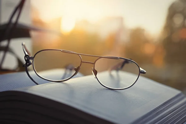 Close-up of a book with glasses on the background of the window. Home rest concept.