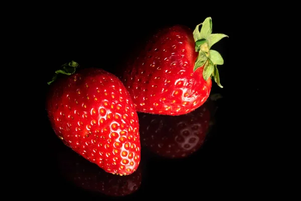 Ripe strawberry on a black background, close-up. Organic fruits.