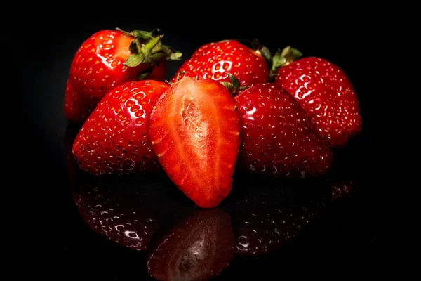 Ripe red strawberries on a black background. Fresh organic berry.