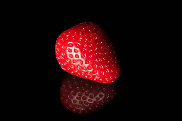 Ripe strawberries on a black background with reflection. Organic food