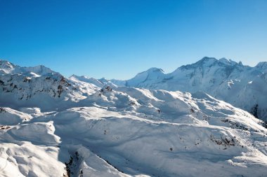 Güneşli bir günde karlı dağların manzarası.