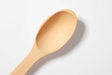 Hafif arka planda, gölgeli ahşap kaşığın üst görüntüsü.