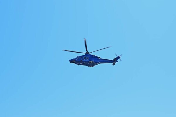 Голубой вертолет летит в голубое небо.