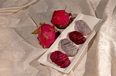 Bir tabakta kırmızı ve beyaz renkli Pitaya meyvesi.