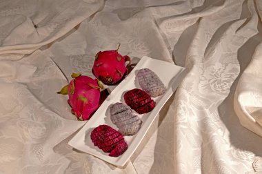 Bir tabakta kırmızı ve beyaz renkli Pitaya meyvesi.