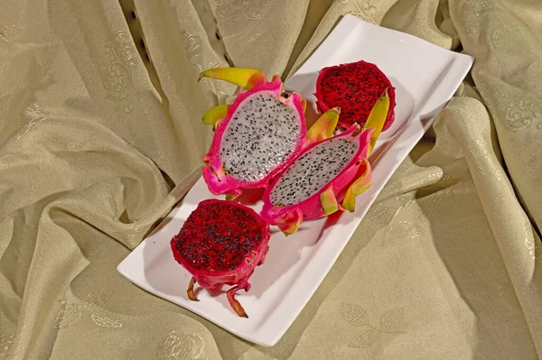 Bir tabakta kırmızı ve beyaz renkli Pitaya meyvesi.