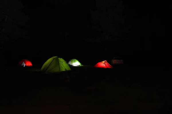 Camping tents with lights on at night.