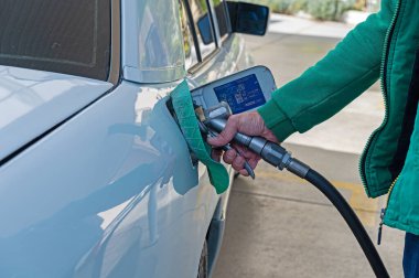 Benzin istasyonu görevlisi arabaya yakıt dolduruyor..