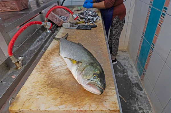A woman cleaning fish in a fish shop.