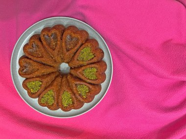 Pembe arka planda bir tabakta kalp şeklinde pasta..