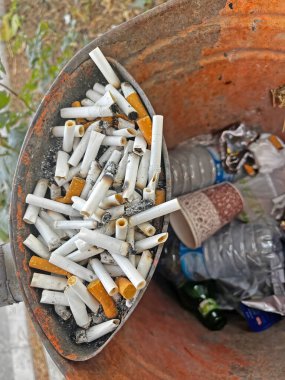 İçinde sigara izmariti olan eski bir çöp kutusu..