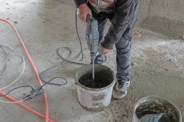 İşçi havanı elektrikli mikserle karıştırıyor.