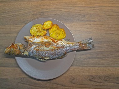 Masadaki tabakta kızarmış balık ve patates parçaları..