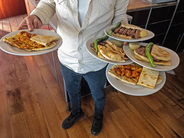 Waiter serving food on a plate in a restaurant.