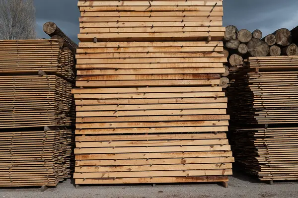 Stacks of boards, board flooring in a sawmill. Warehouse for cutting boards in a sawmill outdoors. Stack of wooden blanks construction material wood timber. Industry.