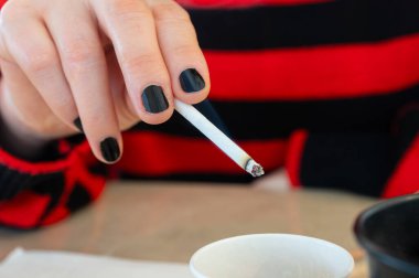 Masada sigara tutan bir kadının yakın çekimi..