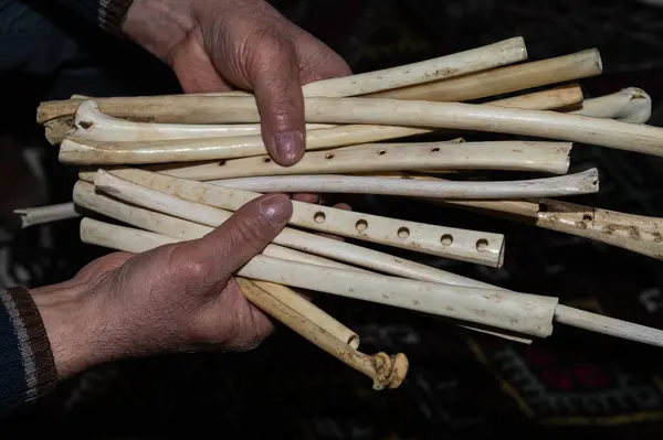 A wind instrument made of eagle wing bones in the hands of a man. Its Turkish name is \