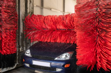 Araba yıkama makinesi. Otomatik yıkama istasyonunda otomatik fırçayla temizlenmiş mavi araba. Otomatik oto yıkama makinesi arkaplanı.